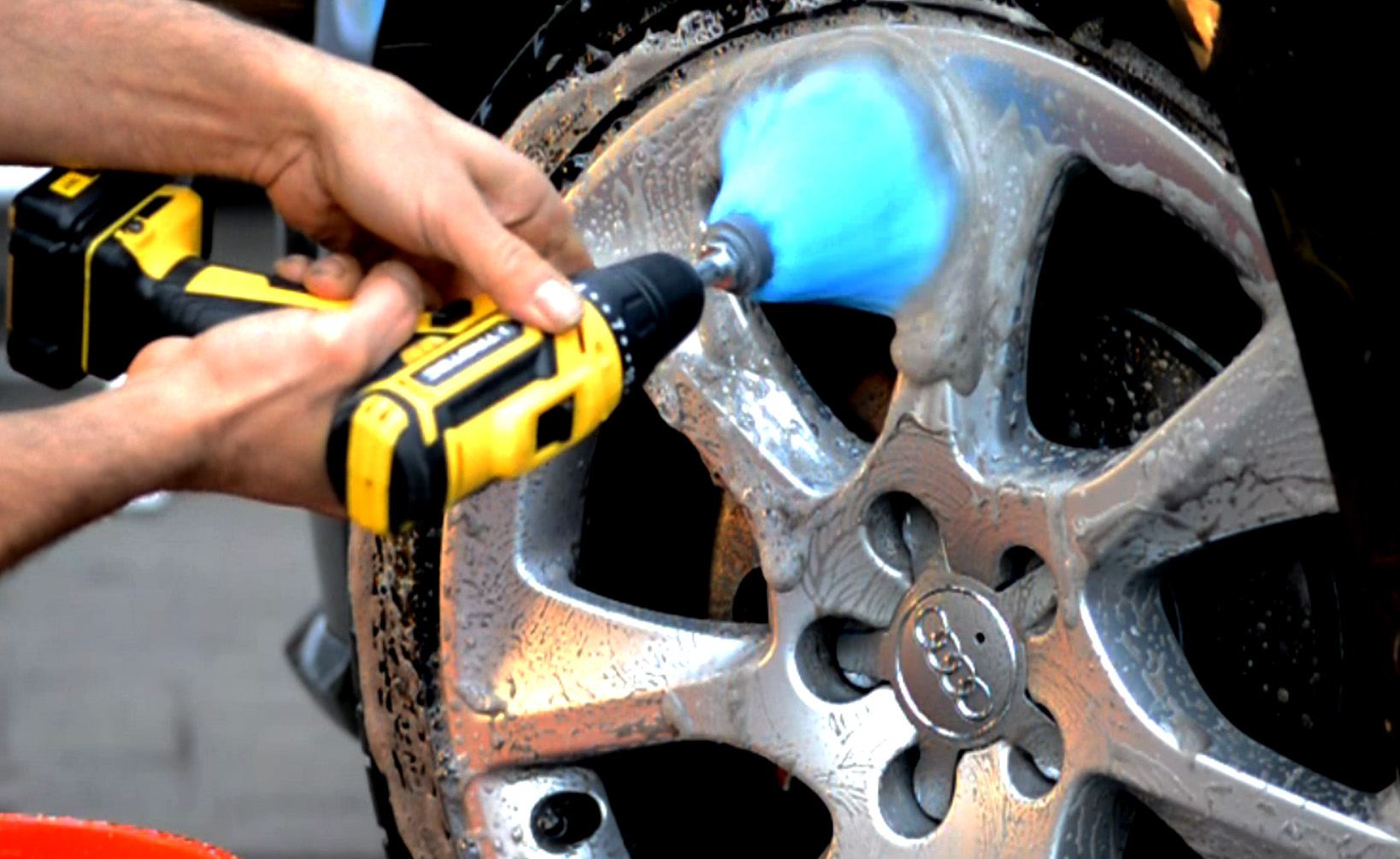 SB-001 Rim Brush in action — foam on an alloy wheel, yellow drill driving the brush